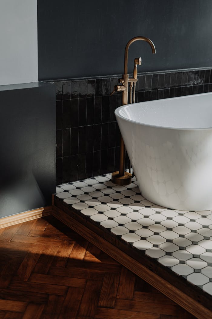brand-03 Luxury bathroom featuring a white bathtub with brass fixtures and stylish tiled flooring.